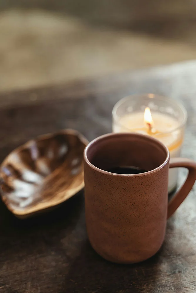 Coffee mug and candle on a wooden table