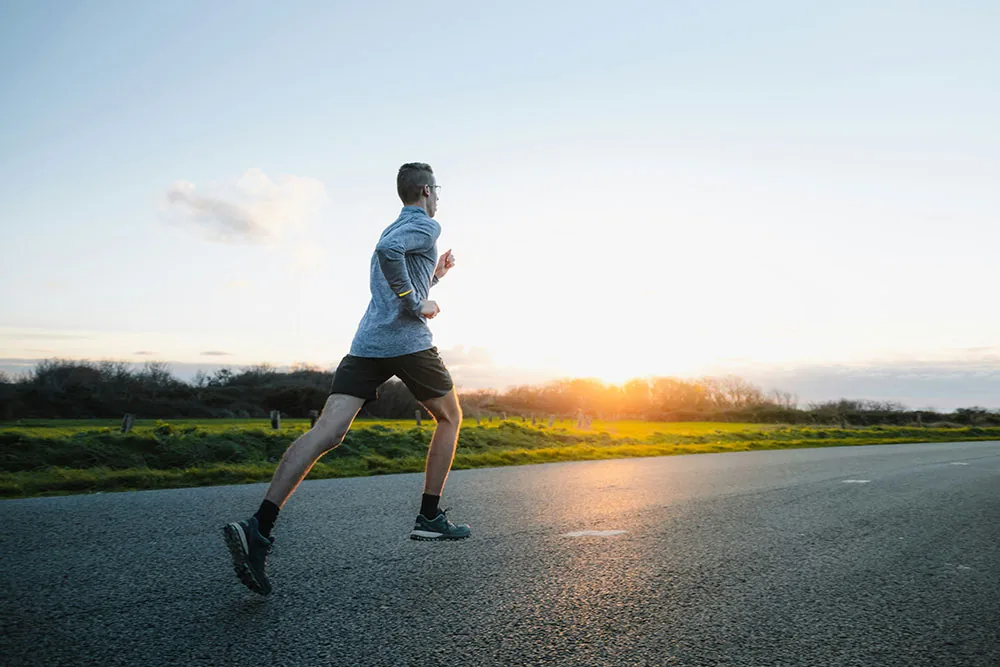 Man running on a road at sunrise